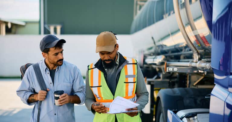 Two truck drivers looking over business documents