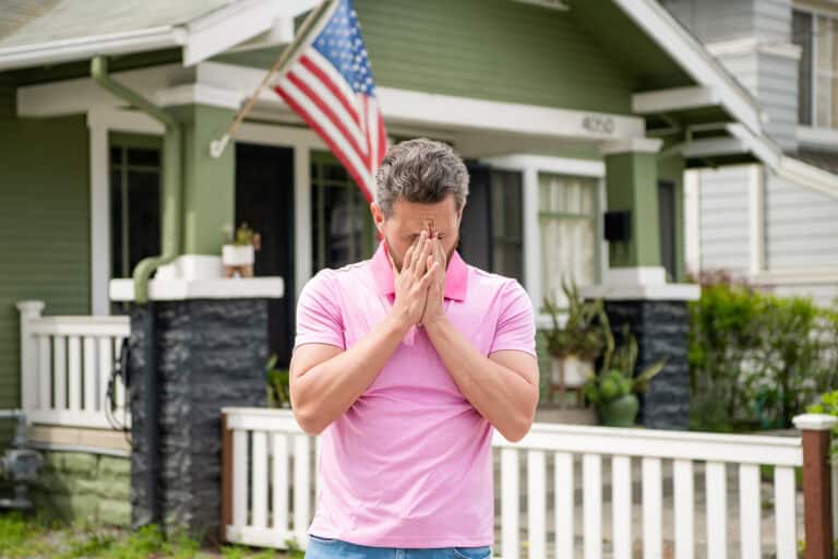 A frustrated homeowner stands in front of his fenced yard.