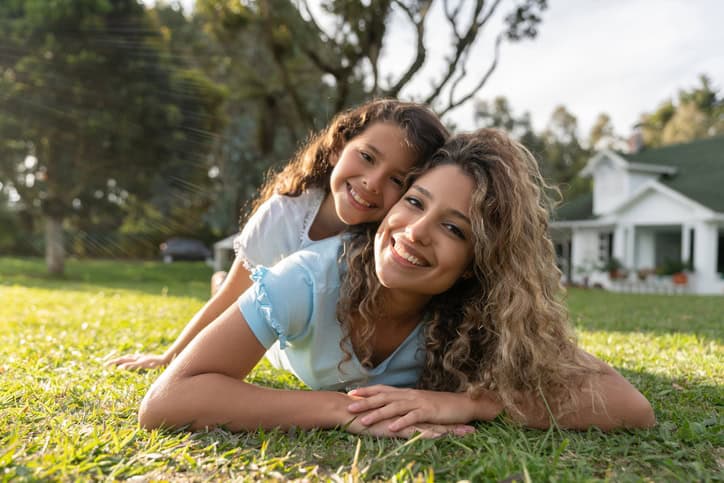 a young mother and daughter in front of their home